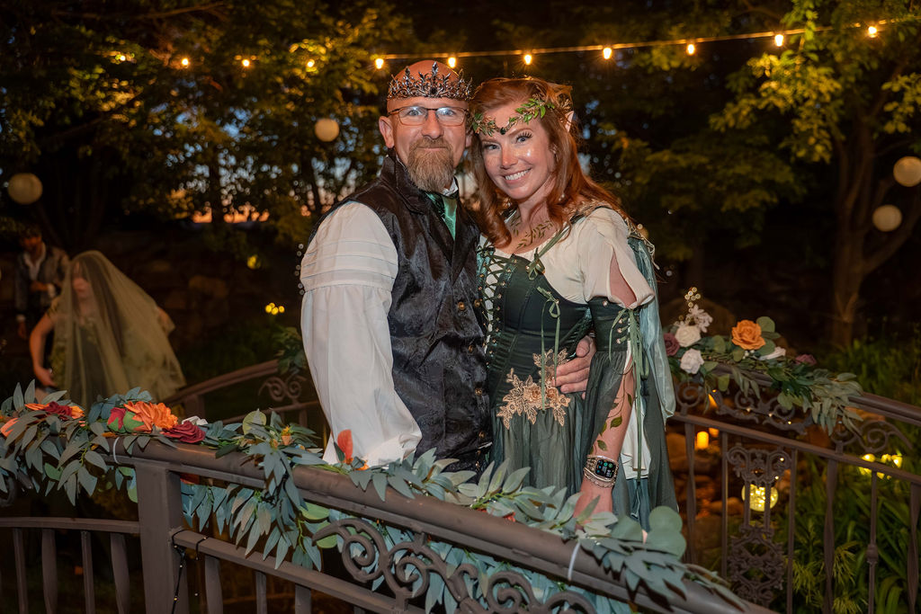 A couple in fantasy attire on the garden bridge at dusk