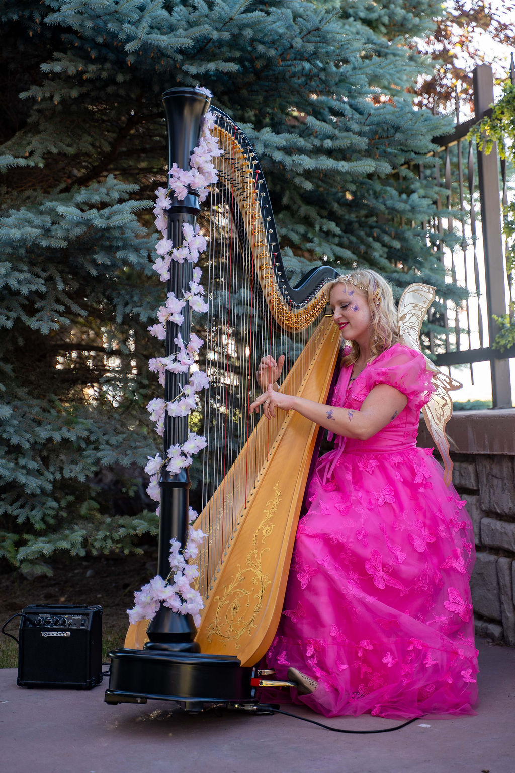 A harpist in a pink gown playing beneath the trees